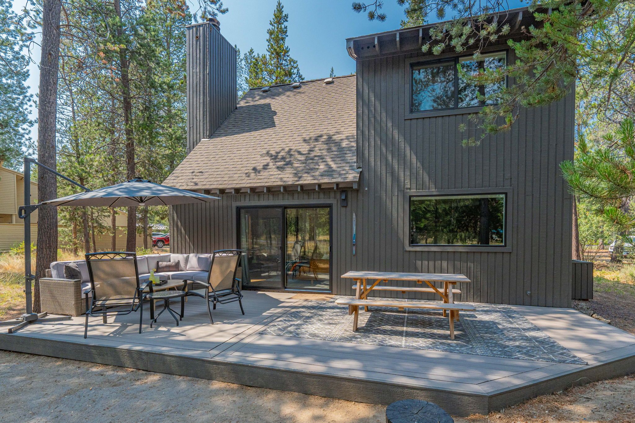 A modern house with a patio, outdoor seating, and a chimney.