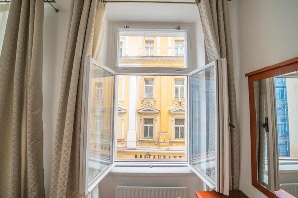 A room with a window overlooking a building labeled 'RESTAURANT' and a radiator below.