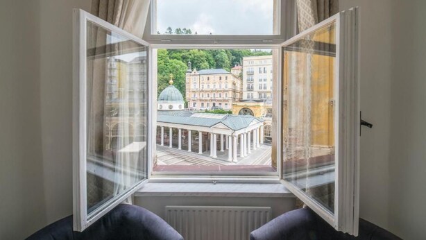 A room with a large window overlooking a building with classical architecture. - Mariánské Lázně Colonnade - Room in the centre (Mariánské Lázně)