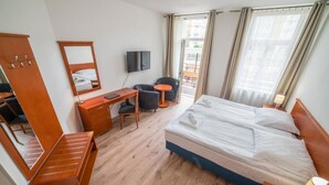 A hotel room with a bed, desk, chair, TV, and a balcony view. - Mariánské Lázně Colonnade - Room in the centre (Mariánské Lázně)