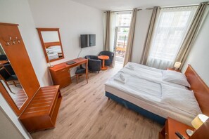 Ein Hotelzimmer mit Bett, Schreibtisch, Stuhl, Fernseher und Balkonblick.