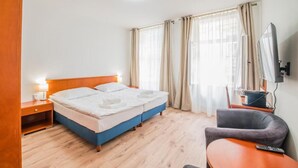 A hotel room with a bed, a desk, a chair, a TV, and curtains. - Mariánské Lázně Colonnade - Room in the centre (Mariánské Lázně)