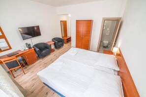 Ein Hotelzimmer mit Bett, Schreibtisch, Stuhl, Fernseher, Kleiderschrank und Badezimmer.