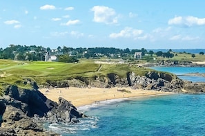 A coastal landscape with a beach, rocky shoreline, and a golf course. - The Unicorn - SAINT LUNAIRE (SAINT LUNAIRE)