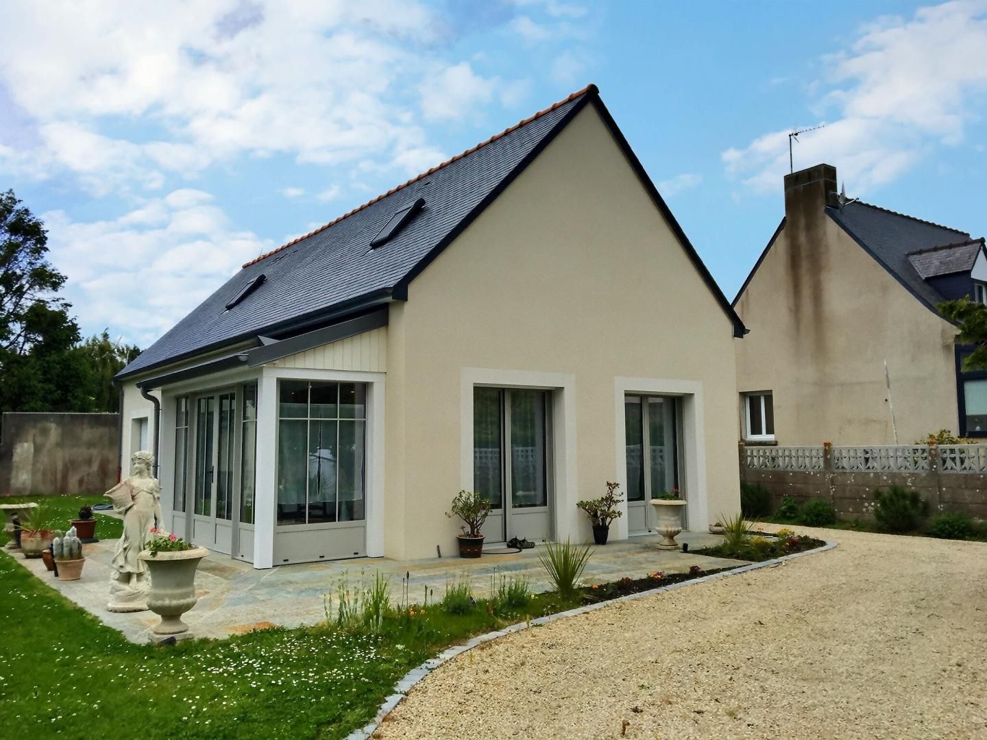 A modern two-story house with a sloped roof, large windows, and a well-maintained garden.