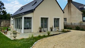 Una casa moderna a due piani con tetto spiovente, ampie finestre e un giardino curato.