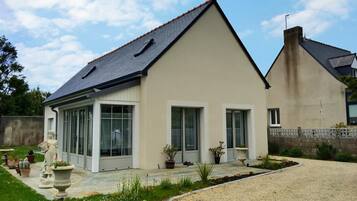A modern two-story house with a sloped roof, large windows, and a well-maintained garden.