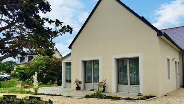 Una moderna casa a due piani con tetto spiovente, ampie finestre e vialetto in ghiaia.