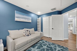 A room with a blue wall, a beige sofa, a starfish-patterned rug, and a white door. - Stylish Coastal Townhome | Premier Resort w/ Pools (Berlin)