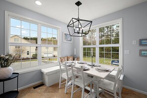 A dining area with a table set for four, large windows, and a hanging light fixture. - Stylish Coastal Townhome | Premier Resort w/ Pools (Berlin)