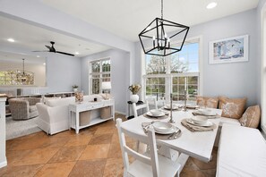 A modern kitchen with white cabinetry, a dining table set for four, and a large window providing a view of the outdoors. - Stylish Coastal Townhome | Premier Resort w/ Pools (Berlin)