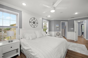 A bedroom with a large bed, a nightstand, a wall clock, and a view of the outdoors. - Stylish Coastal Townhome | Premier Resort w/ Pools (Berlin)