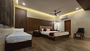 Une chambre d’hôtel avec deux lits, un ventilateur de plafond, un appareil de climatisation et une petite table.