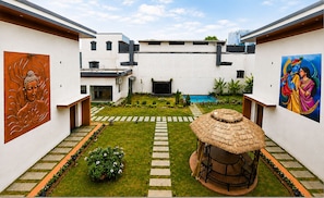A courtyard with a central seating area, a pool, and two large wall paintings.