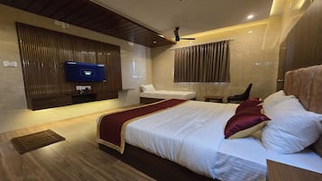 Una habitación de hotel moderna con una cama grande, un televisor montado en la pared, un ventilador de techo y una pared con textura de mármol.