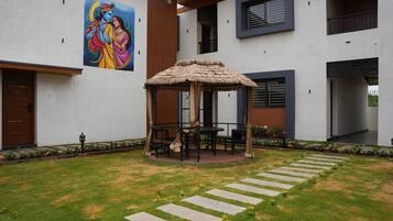 Un edificio moderno con un porche de paja, asientos exteriores y un mural en la pared.