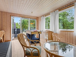 A wooden-paneled room with a foosball table, wicker chairs, and a glass table. - "Karelia" - 900m from the sea by Interhome (Væggerløse)