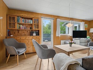A cozy living room with a wooden bookshelf, a television, and a dining area with a table and chairs. - "Karelia" - 900m from the sea by Interhome (Væggerløse)