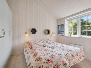 A bedroom with a bed, wooden walls, a window with a view, and wall-mounted lights. - "Heidrun" - 400m from the sea by Interhome (Væggerløse)
