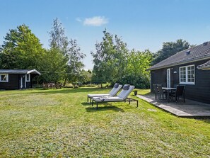 A backyard with a lawn, two lounge chairs, a small table, and a deck. - "Heidrun" - 400m from the sea by Interhome (Væggerløse)