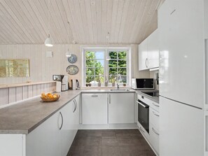A modern kitchen with white cabinetry, a built-in oven, and a microwave. - "Heidrun" - 400m from the sea by Interhome (Væggerløse)