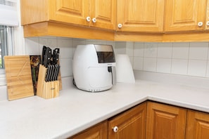 Cozinha com armários de madeira, bancada, cafeteira e porta-facas.