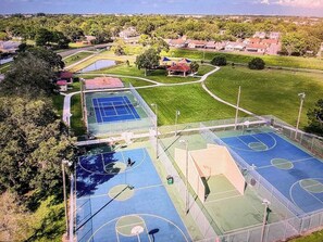 An aerial view of a sports complex with multiple courts, including basketball and tennis courts, surrounded by green spaces and residential buildings. - Waterfront ~ Heated Saltwater Pool ~ 8 mi to Beach (Largo)