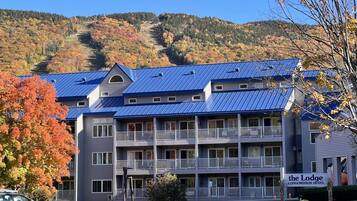 A multi-story building with balconies, a sign indicating it's a condominium hotel, and a mountainous backdrop.