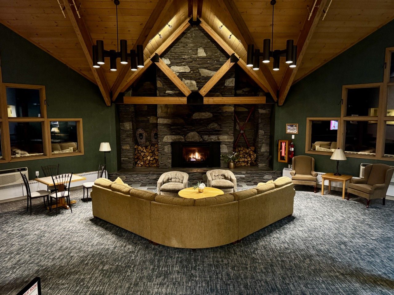 A cozy living room with a stone fireplace, wooden beams, and comfortable seating.