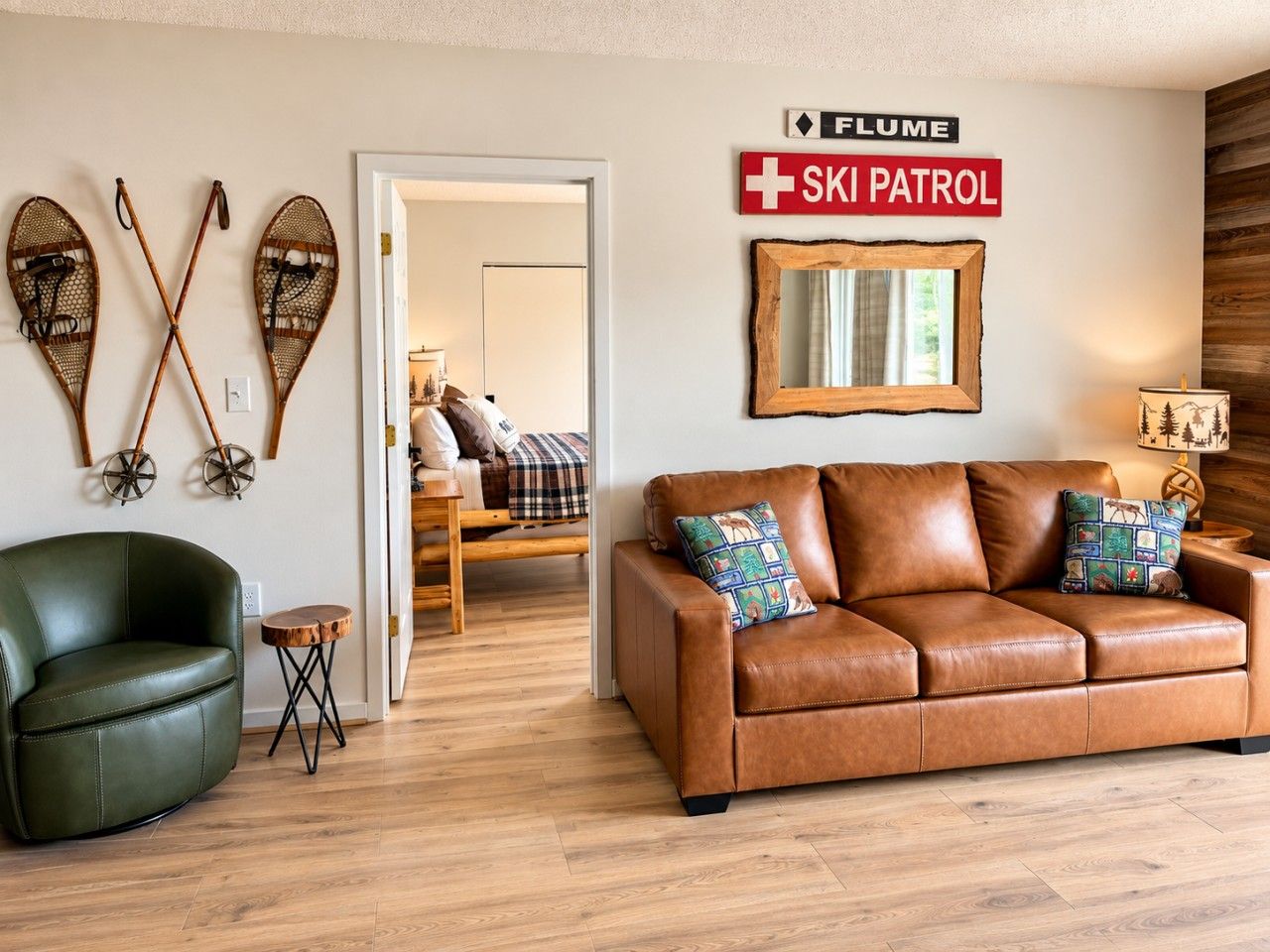 A living room with a leather sofa, a green armchair, and a wooden side table. There is a sign that reads 'FLUME SKI PATROL' on the wall.
