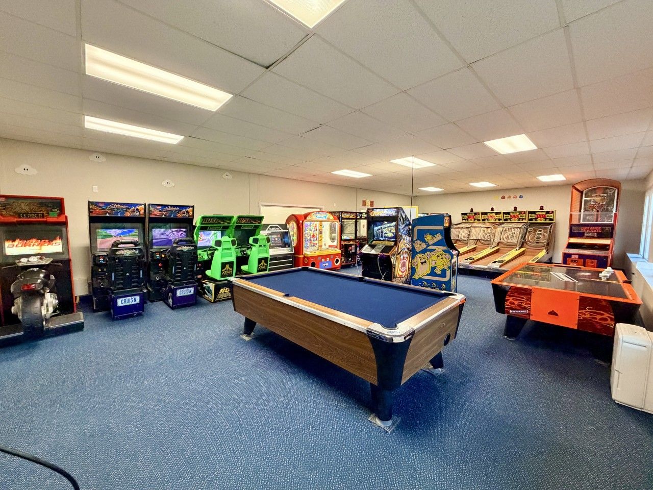 Une salle avec une table de billard, des jeux d’arcade et un distributeur automatique.