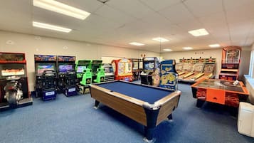 Une salle avec une table de billard, des jeux d’arcade et un distributeur automatique.