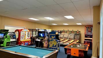Een recreatieruimte met biljarttafels en verschillende spelautomaten.