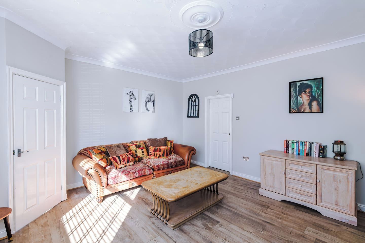 A room with a sofa, a bench, a cabinet, and artwork on the walls.