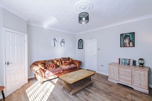 Ein Zimmer mit einer Couch, einer Bank, einem Schrank und Kunstwerken an den Wänden.