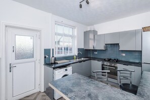 Cozinha compacta com máquina de lavar embutida, fogão a gás e pia.