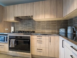 A modern kitchen with wooden cabinetry, a built-in oven, and a gas stove.