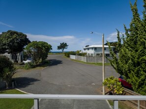 A residential street with a white house, a parked car, and a clear blue sky. - Beachside Bliss - One Bedroom Apartment (Napier)