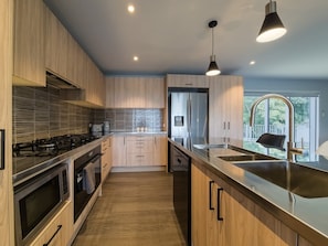 A modern kitchen with wooden cabinets, stainless steel appliances, and a large island with a sink.