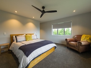 A bedroom with a bed, a chair, a ceiling fan, and a window.