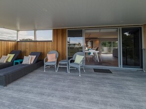 An open-plan living area with a sofa set, chairs, and a dining table. - Beachside Bliss - One Bedroom Apartment (Napier)