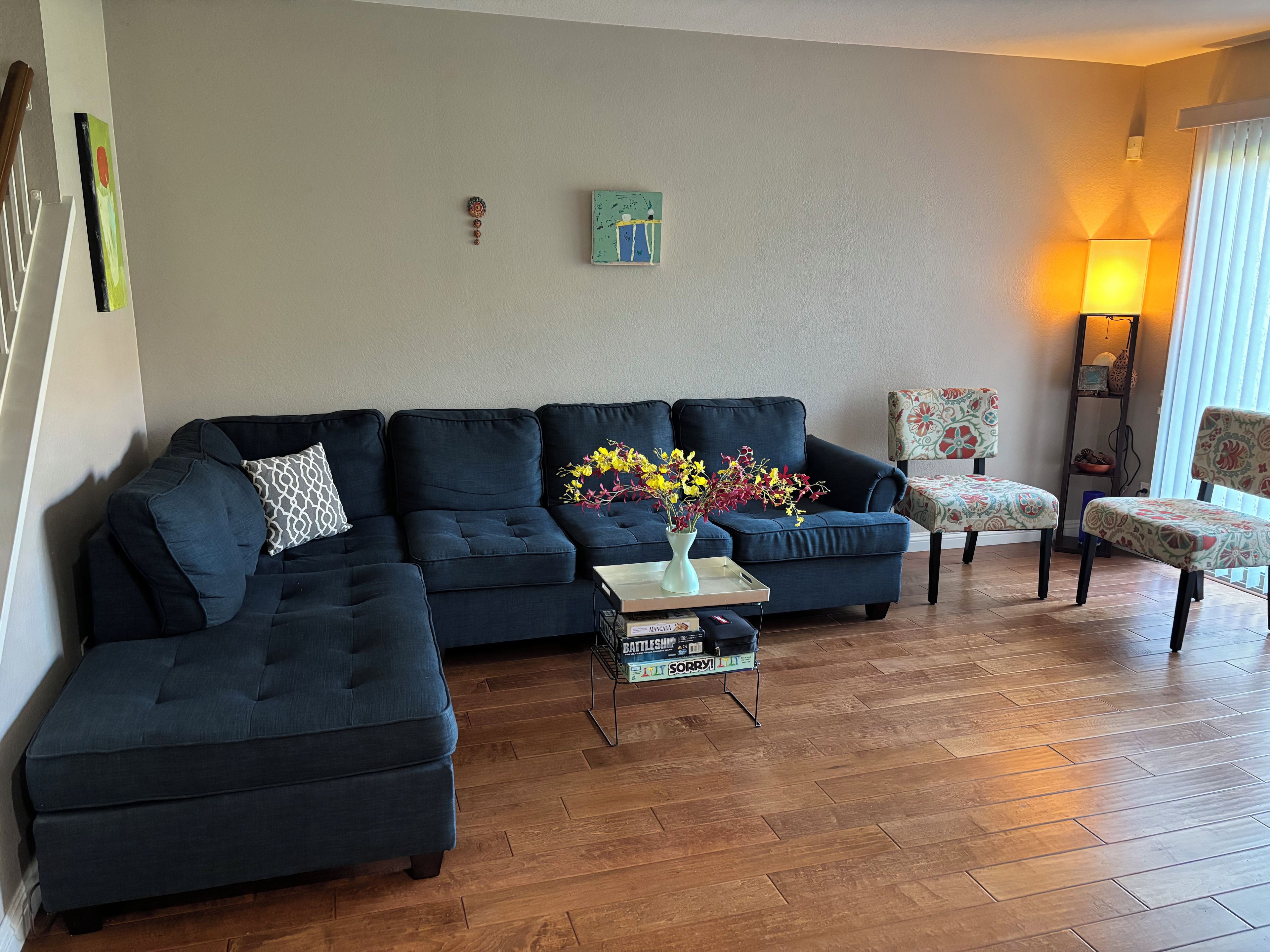 A living room with a sectional sofa, a coffee table with a vase, and a patterned armchair.