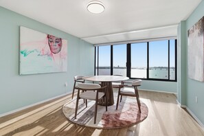 A modern room with a round table, chairs, a large window, and artwork on the walls. - Downtown Sarasota Penthouse with Post card waterfront views (Sarasota)