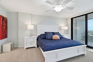 A bedroom with a bed, two bedside tables, a ceiling fan, and a large window. - Downtown Sarasota Penthouse with Post card waterfront views (Sarasota)