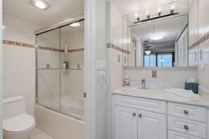 A bathroom with a glass-enclosed shower, a white toilet, a vanity with a mirror, and a sink. - Downtown Sarasota Penthouse with Post card waterfront views (Sarasota)
