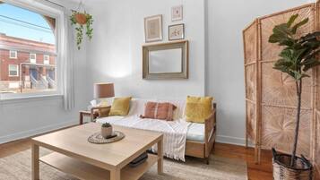 A cozy living room with a sofa, a coffee table, and a large window.