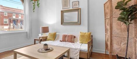 A cozy living room with a sofa, a coffee table, and a large window.