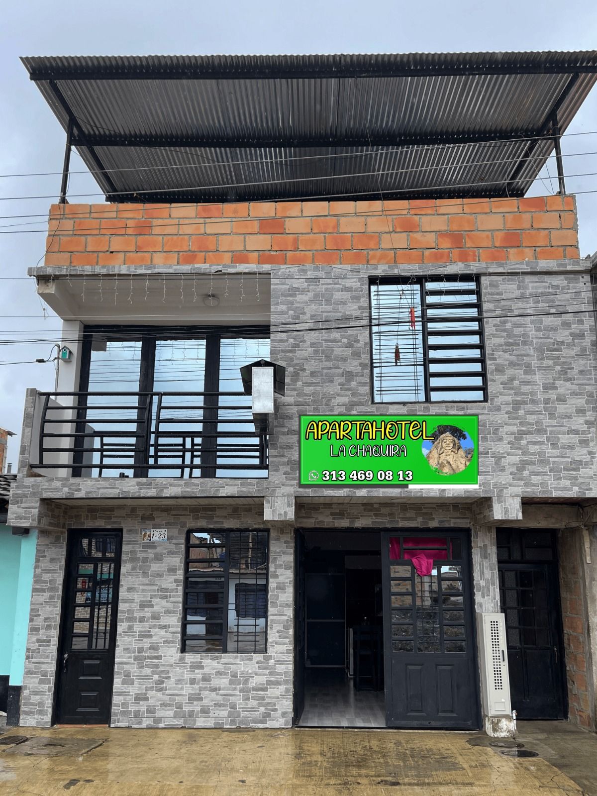 A two-story building with a sign for 'APARTAHOTEL LA CHAQUIRA' and a contact number.