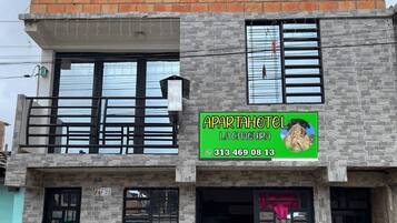 A two-story building with a sign for 'APARTAHOTEL LA CHAQUIRA' and a contact number.
