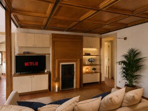 Ein Wohnzimmer mit Kamin, Fernseher und einer Zimmerpflanze.